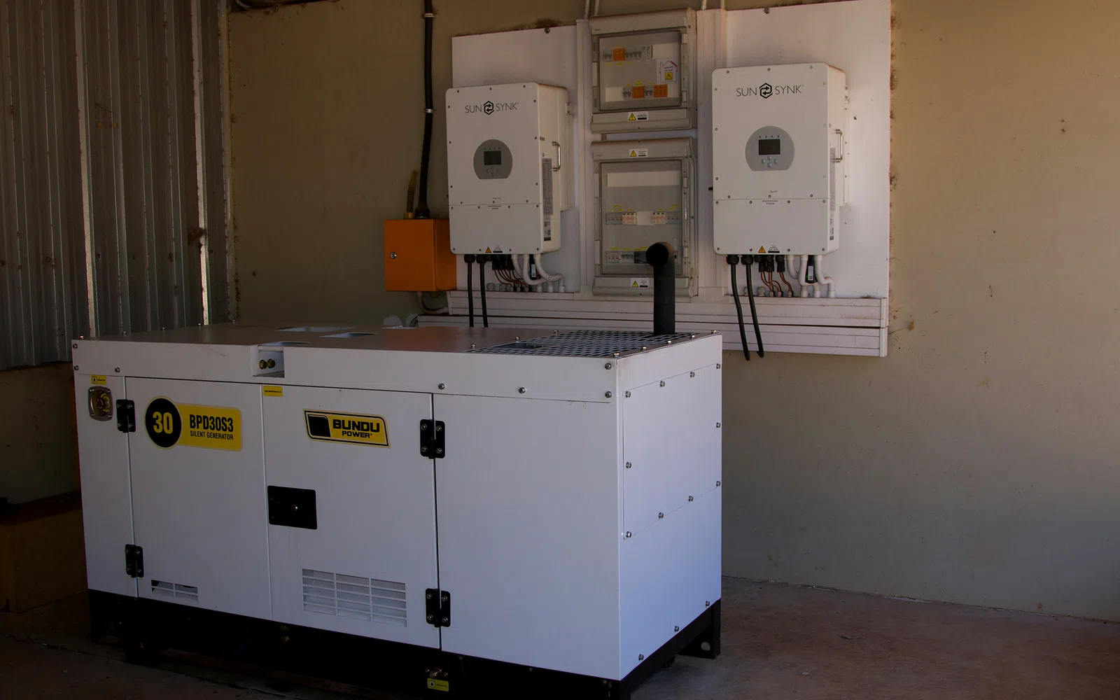 Backup generator installed beside wall-mounted solar inverters and electrical panels