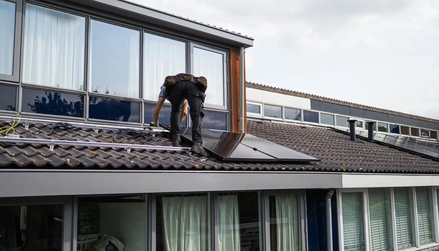 Solar installer working beside photovoltaic modules on a residential rooftop