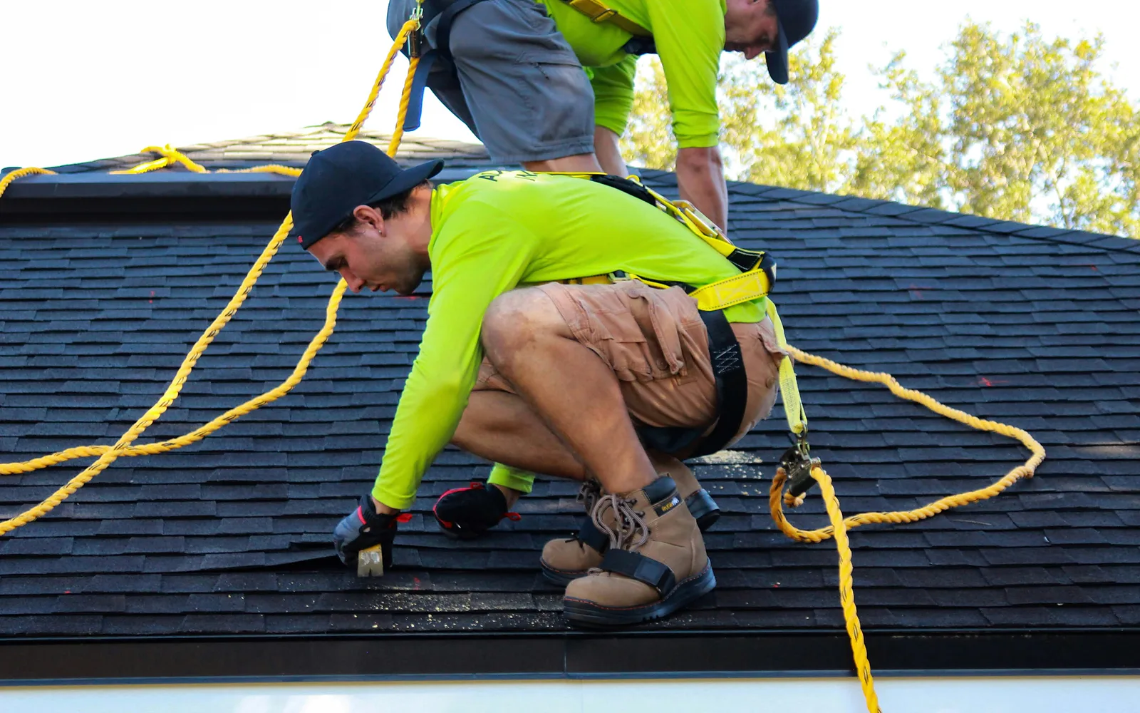 Solar installers working on a pitched roof with fall-protection equipment
