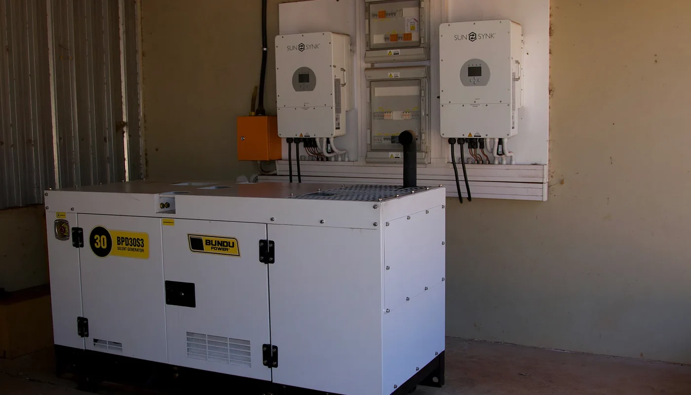 Backup generator installed beside wall-mounted solar inverters and electrical panels