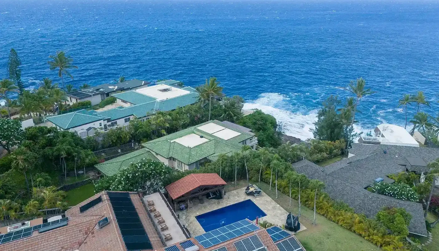 Aerial view of tropical homes with rooftop solar arrays, illustrating complete residential system scope