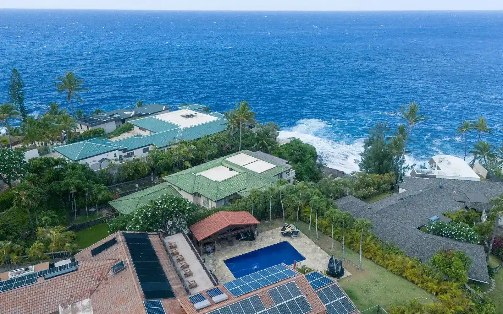Aerial view of tropical homes with rooftop solar arrays, illustrating complete residential system scope