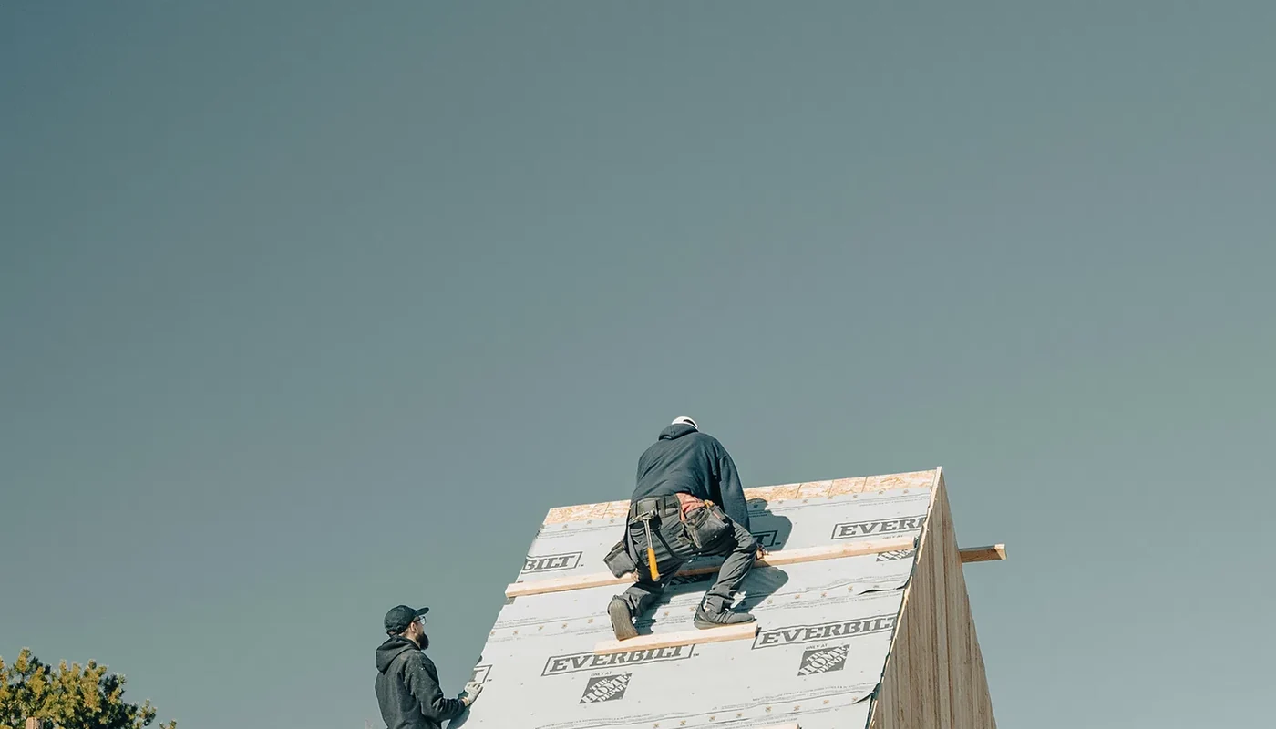 Workers assembling roof framing before permits and structural approval