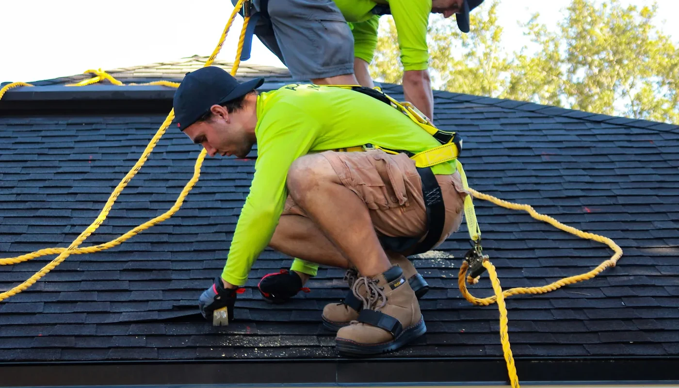 Solar installers working on a pitched roof with fall-protection equipment