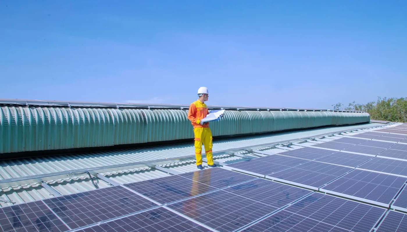 Solar technician inspecting a rooftop photovoltaic array with a clipboard